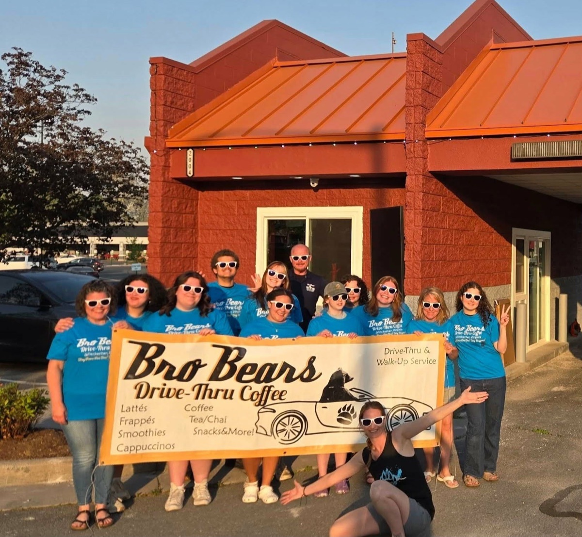 Bro Bears staff holding a Bro Bears banner in front of the storefront